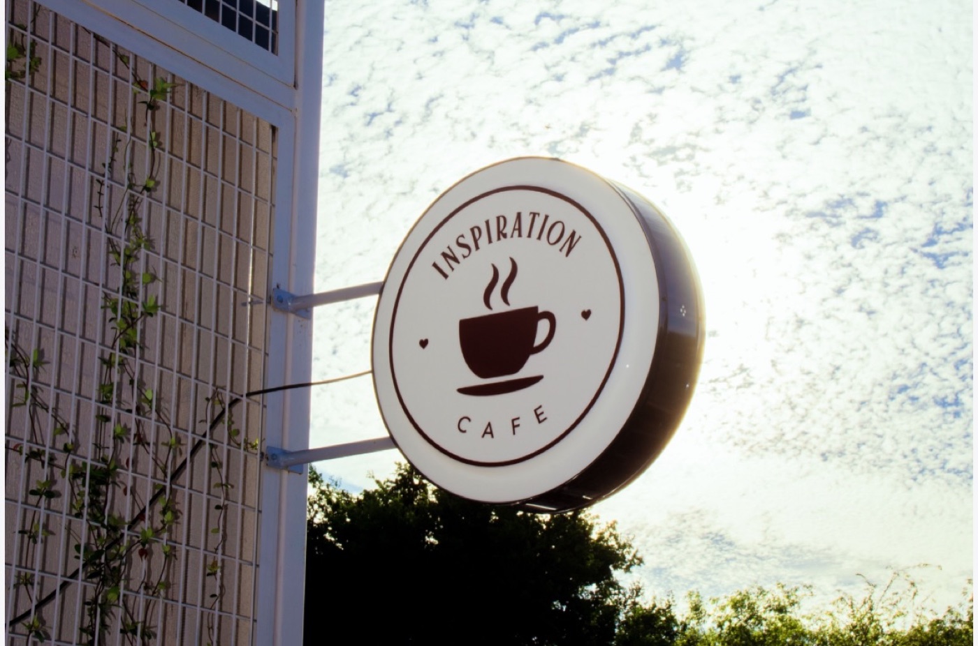 The round Inspiration Café sign hanging outside the shop