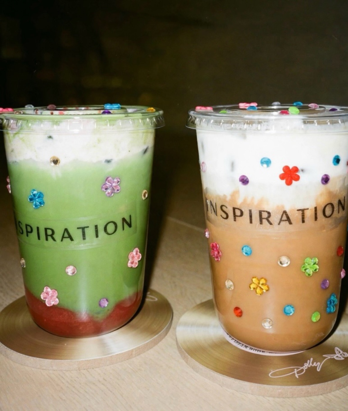 A strawberry matcha and a latte, both cups decorated with gems