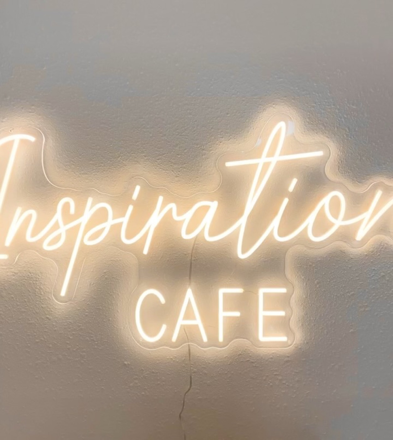 The cream neon Inspiration Café sign
